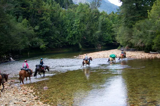 Cabalgata cruzando el río en el valle de Cochamó